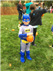 A child in a Batman costume, holding a pumpkin
